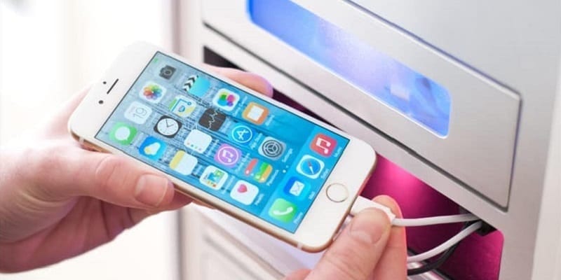 close up of person plugging in phone in cell phone charging locker