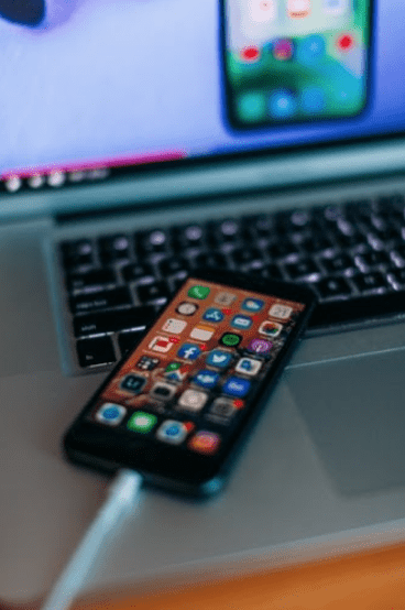 Black iPhone charging plugged into MacBook Pro laptop