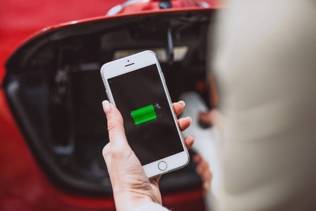 female hands with mobile battery charging electro car