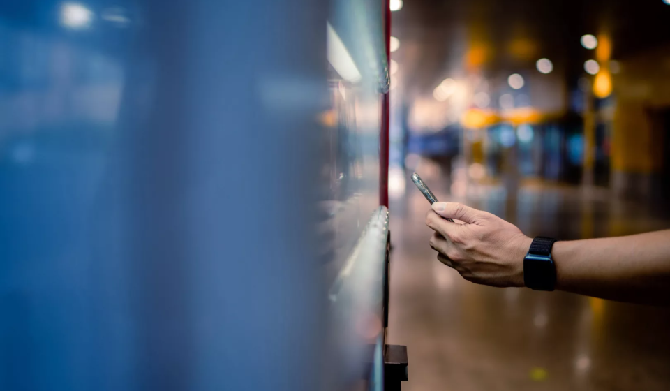 Asian man paying with smartphone to vending machine.